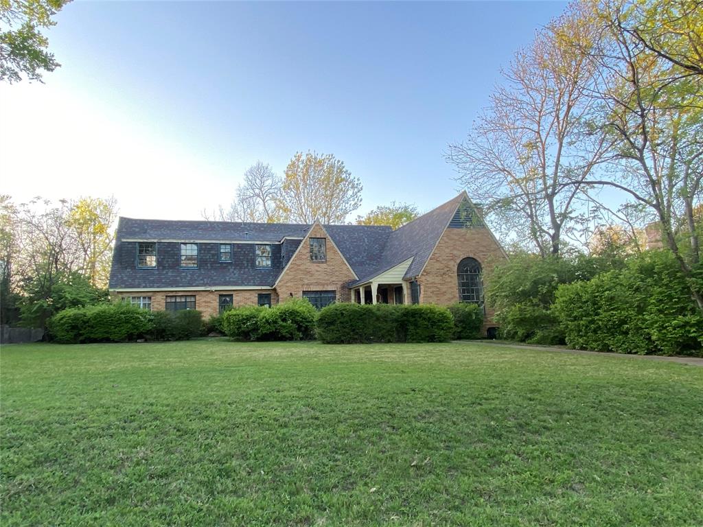 a view of a house next to a big yard and large trees