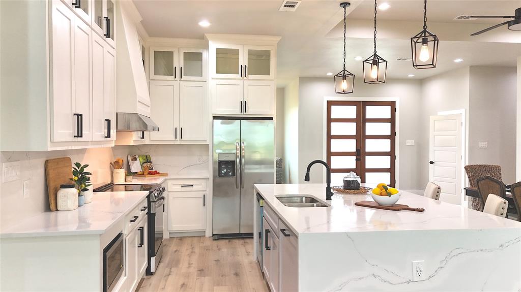 a kitchen with stainless steel appliances granite countertop a sink a stove and a refrigerator