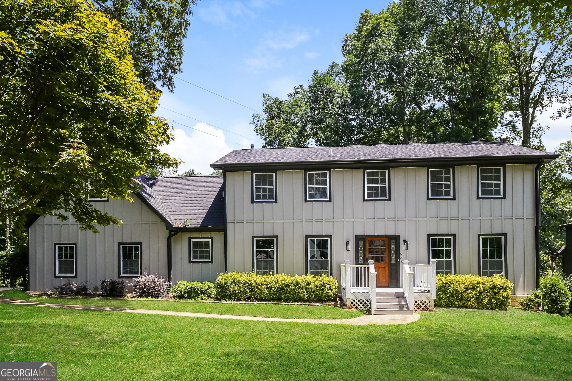 a front view of a house with a yard and trees