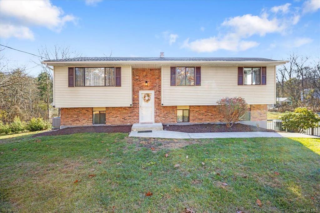 Split foyer home with central air condition unit and a front yard