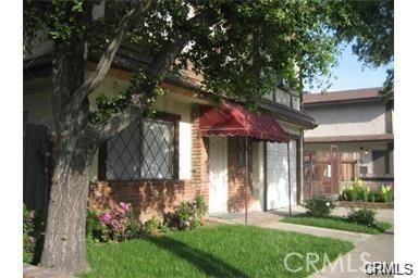 a view of a house with brick walls and a yard with a large tree