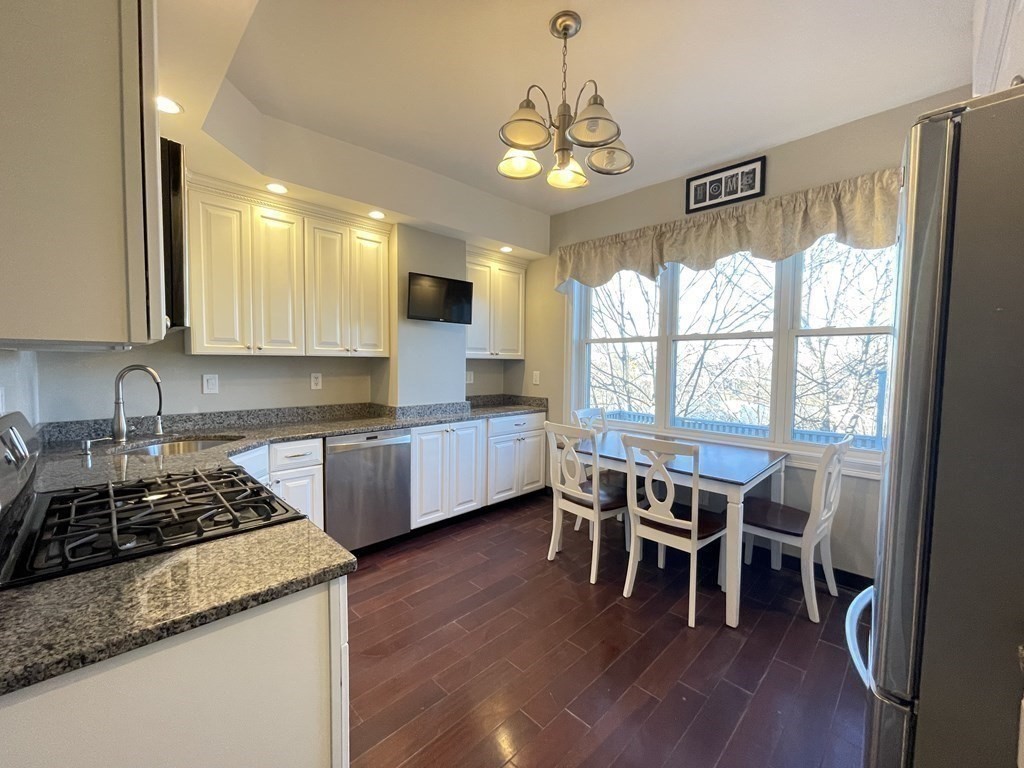 a kitchen with stainless steel appliances granite countertop wooden floors and white cabinets