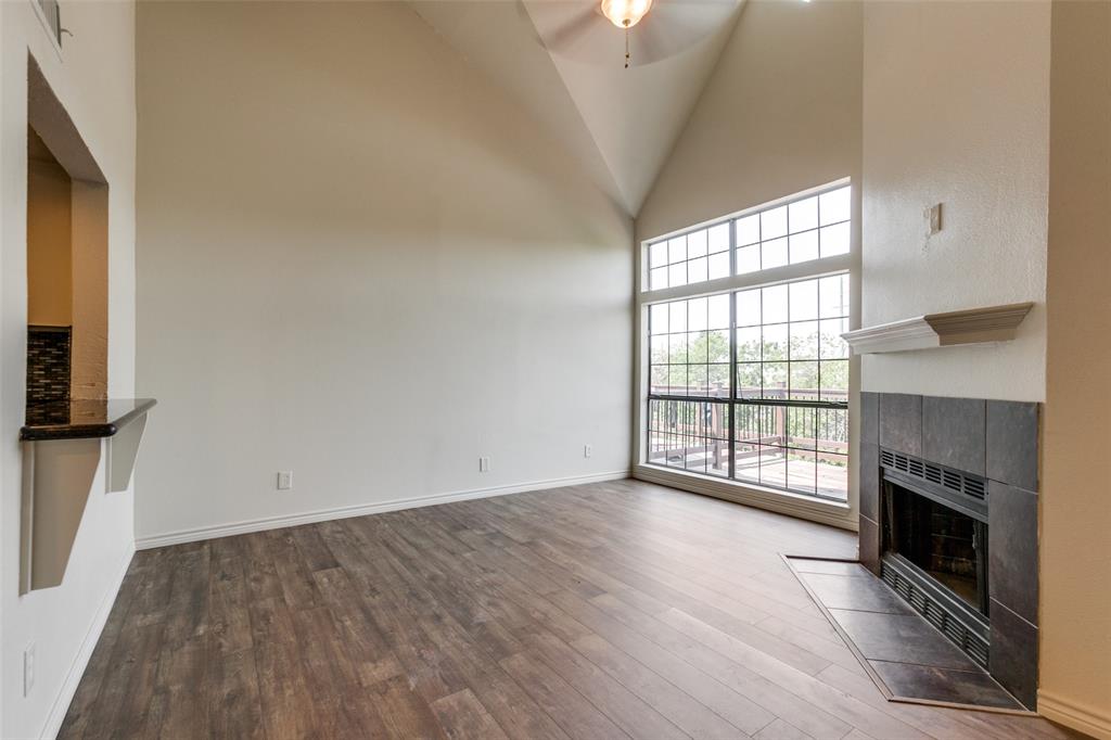 an empty room with wooden floor fireplace and windows