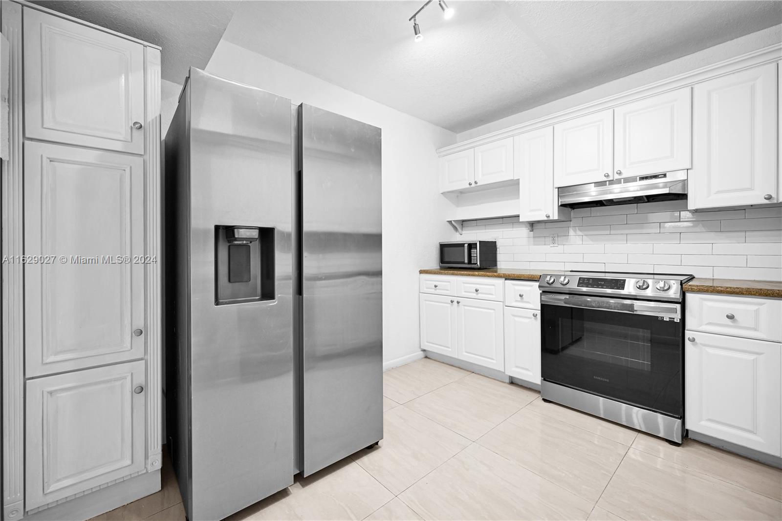 a kitchen with stainless steel appliances granite countertop white cabinets and a refrigerator