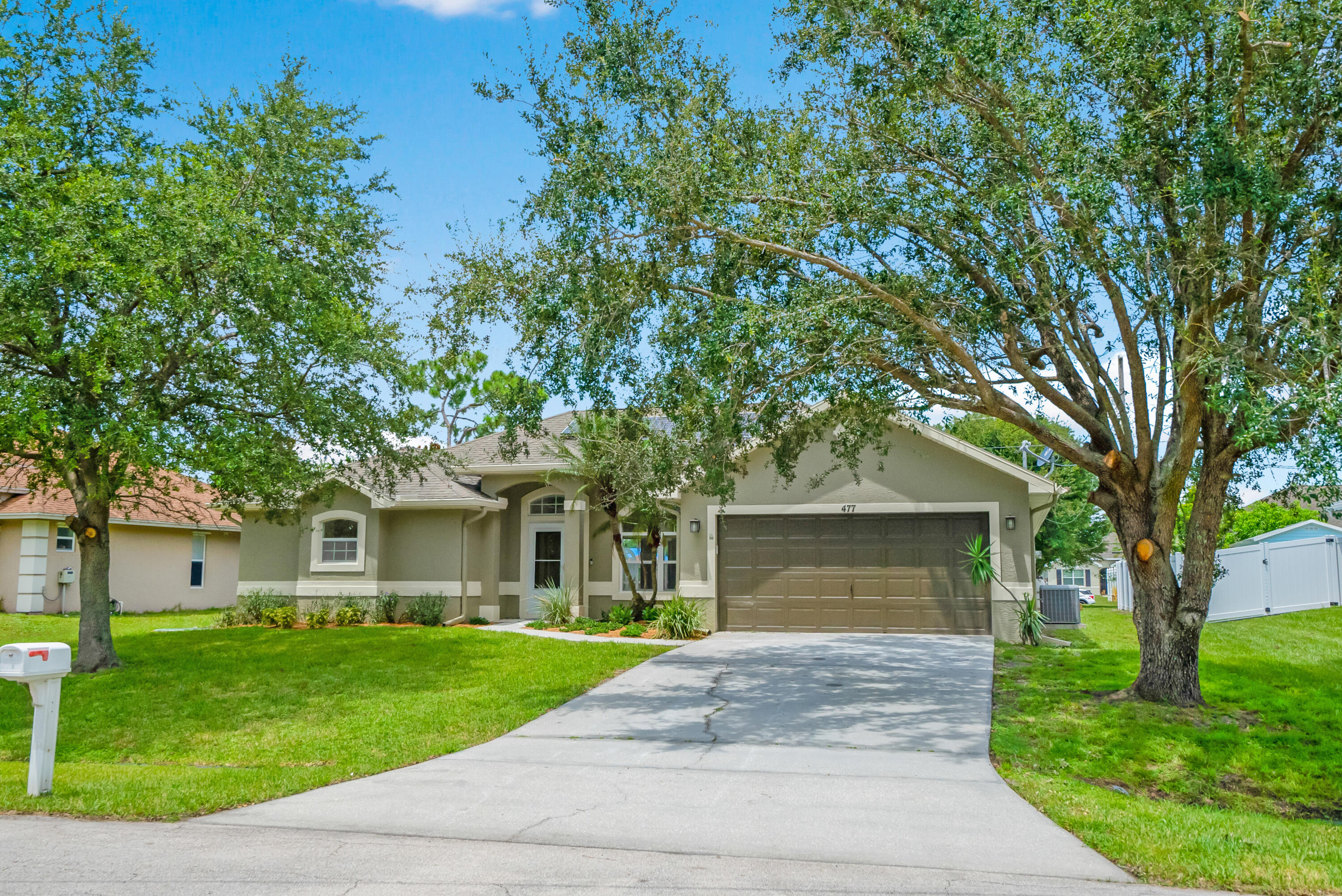 a front view of a house with a garden and trees