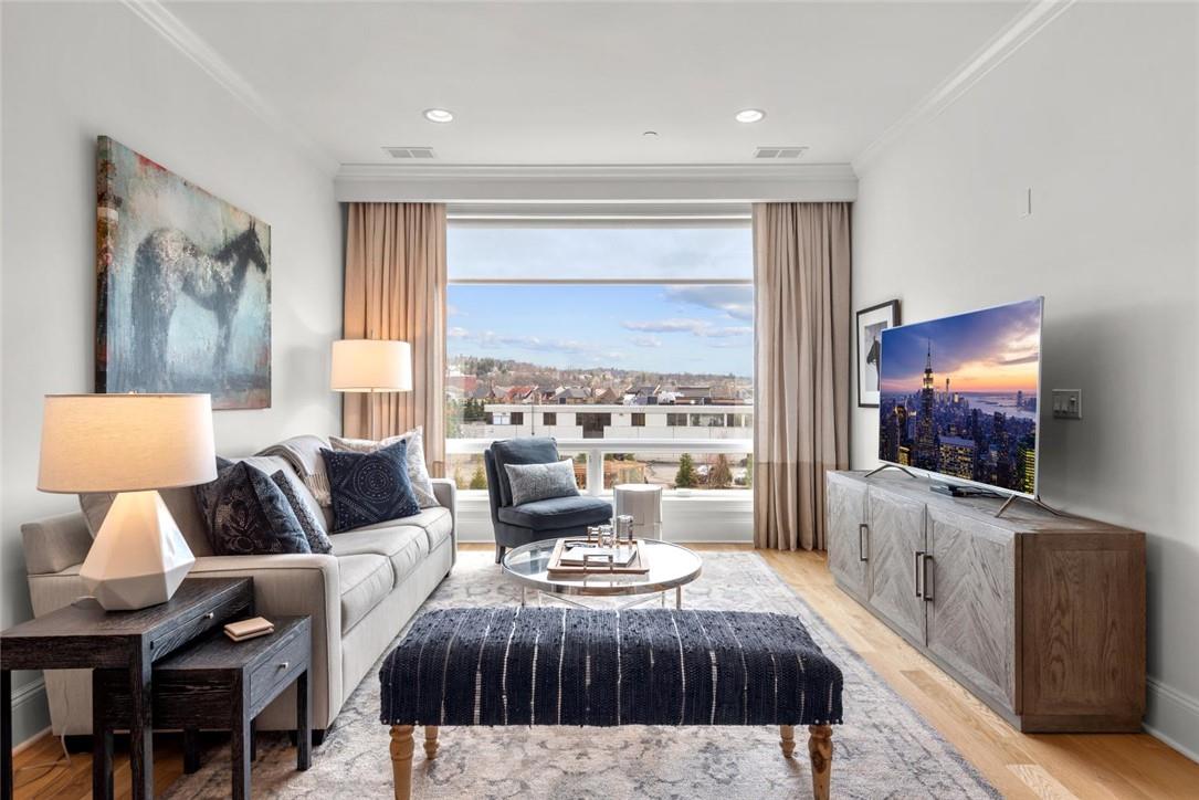 Living room with ornamental molding, plenty of natural light, and light wood-type flooring