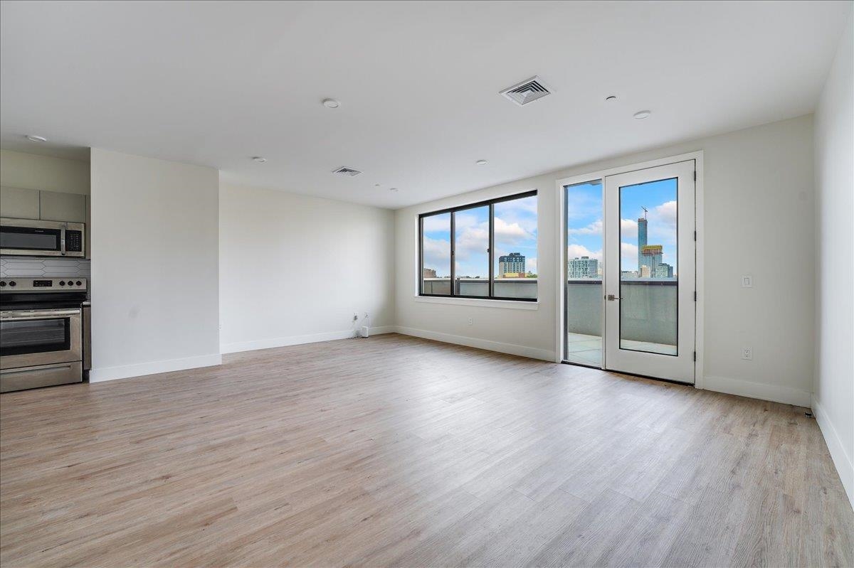 a view of an empty room with a window and wooden floor