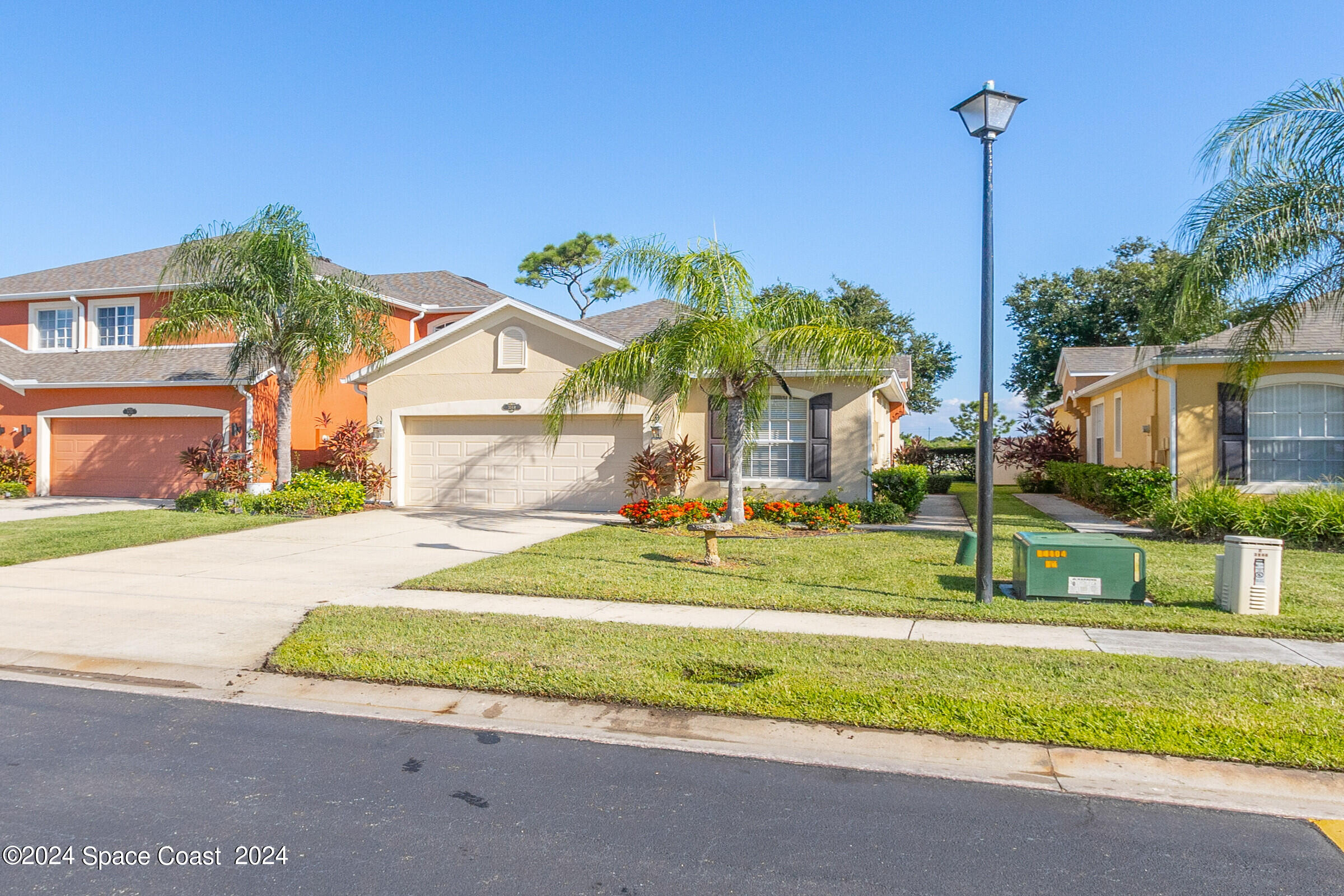 a house view with a big yard plants and palm trees