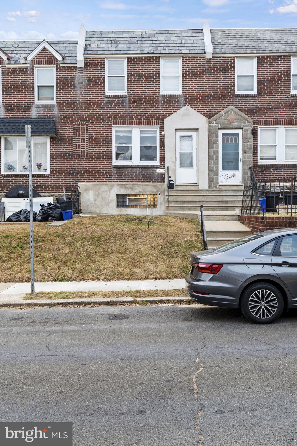 a front view of a house with parking space and a car parked in front of it