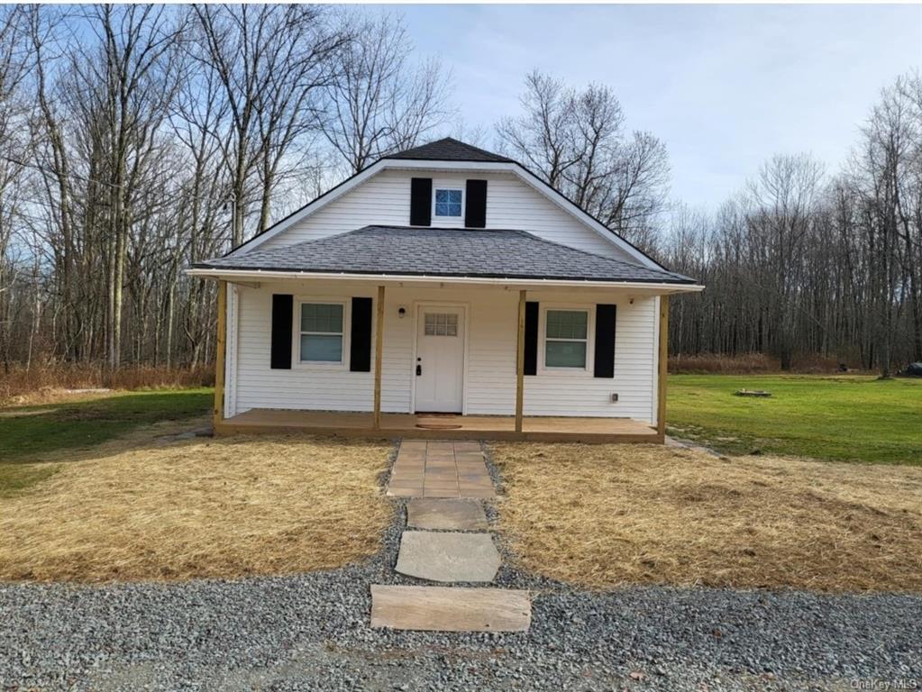 View of front of property with covered porch and a front lawn