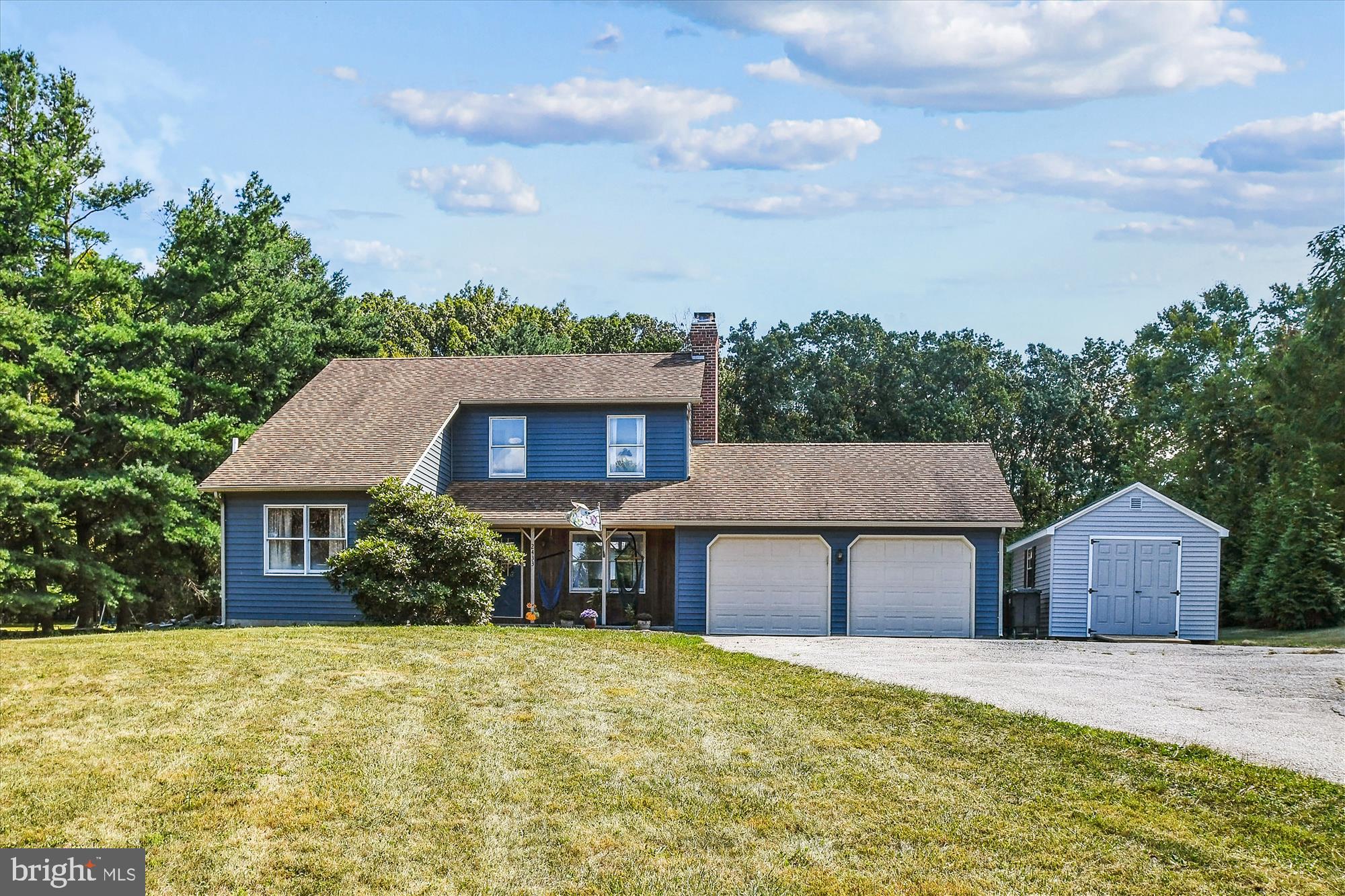 a front view of house with yard and trees in the background