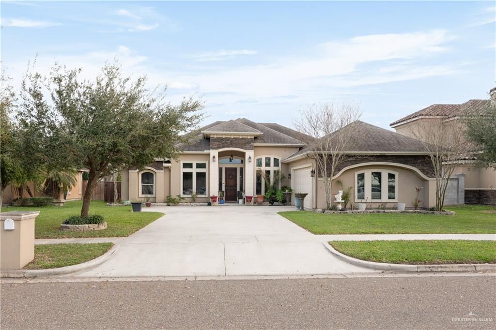 Mediterranean / spanish home featuring a garage and a front lawn