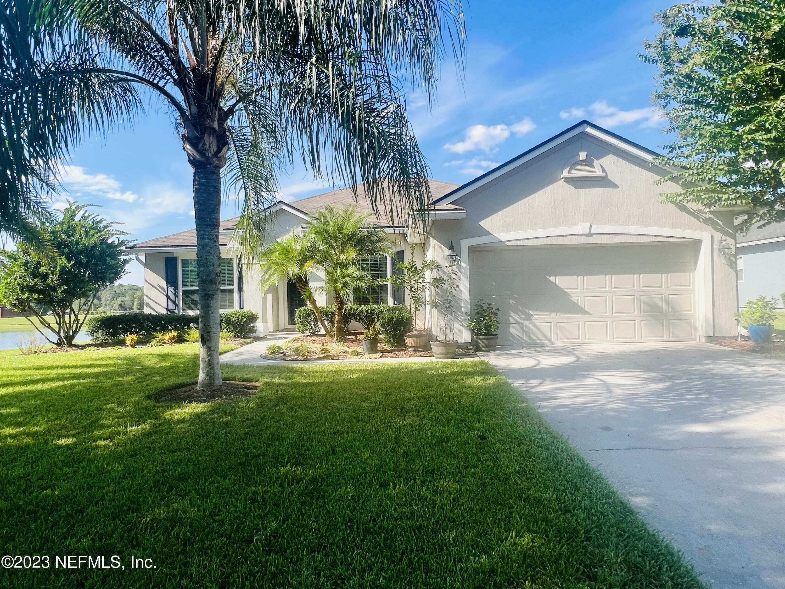 a view of a house with a yard and palm trees