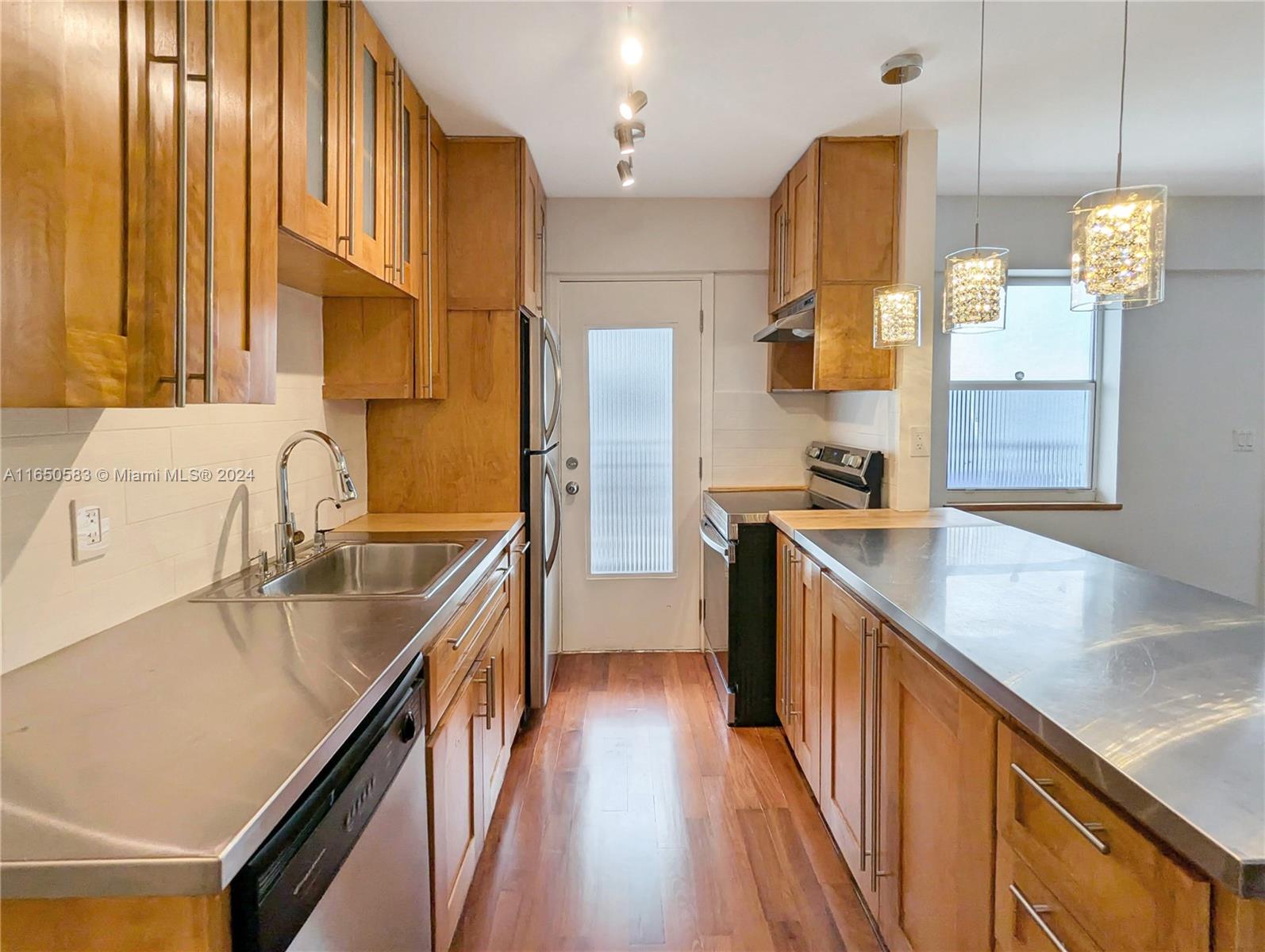 a kitchen with stainless steel appliances granite countertop a sink a stove and a refrigerator