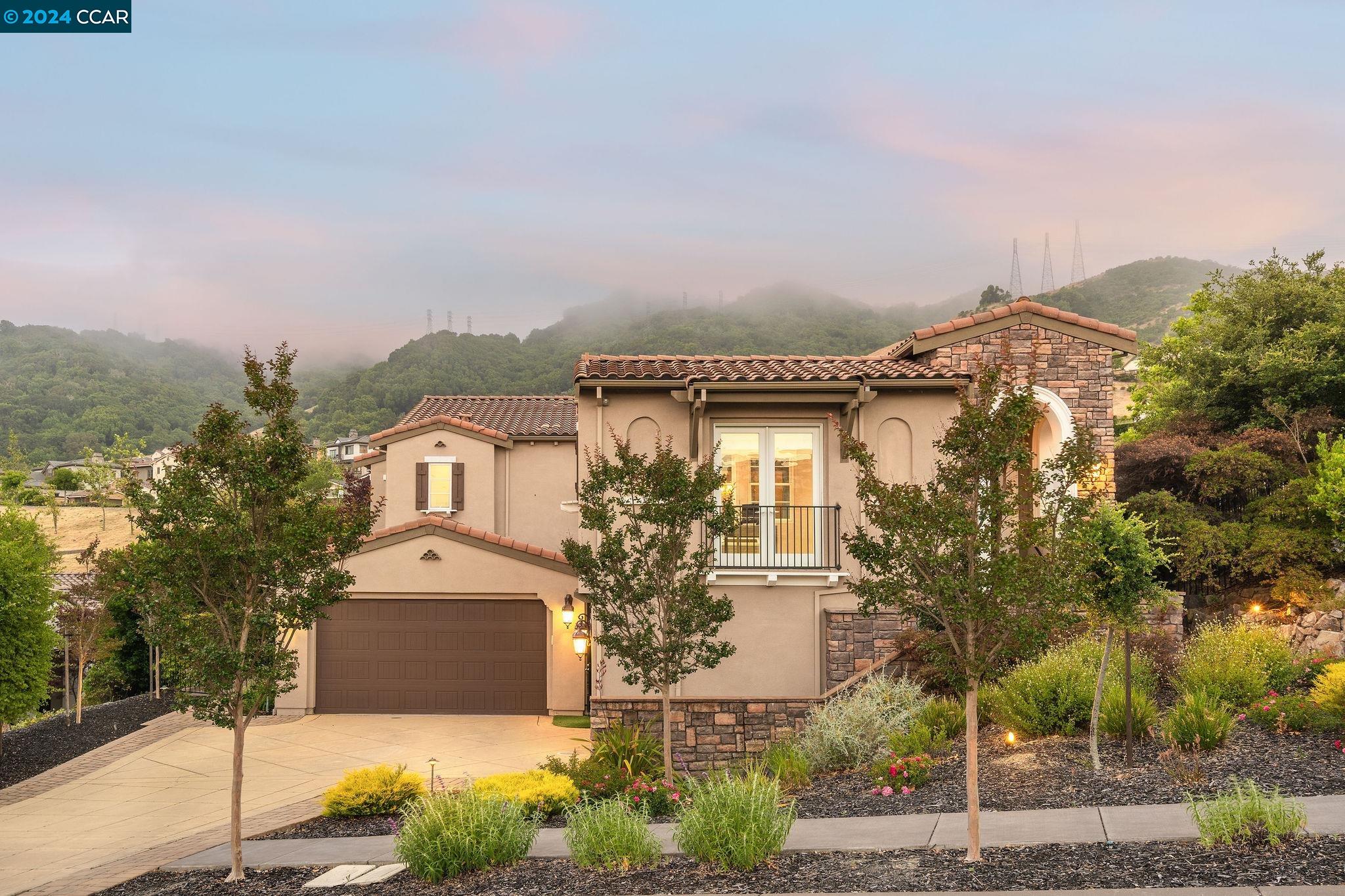 a front view of a house with a yard and mountain view in back