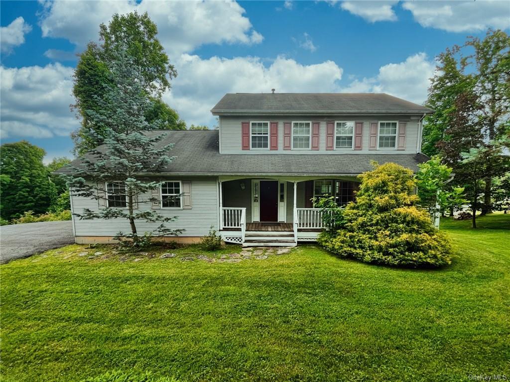 View of front facade featuring covered porch and a front yard