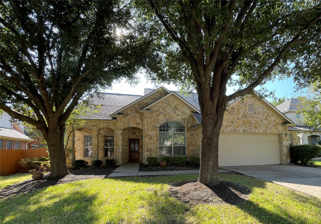 a front view of a house with a yard from a large tree