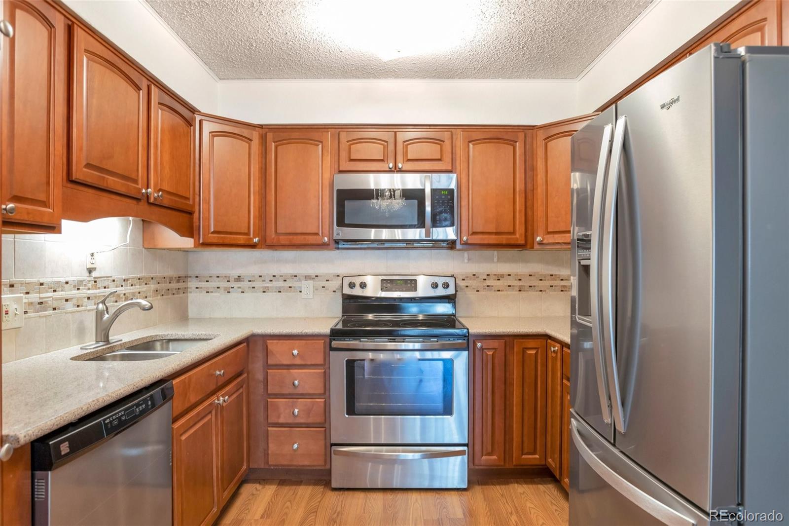 a kitchen with stainless steel appliances granite countertop a stove a sink and a refrigerator