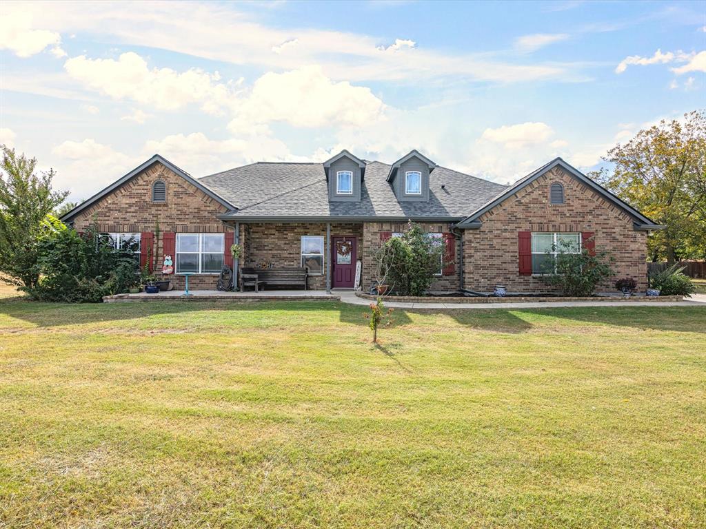 a front view of house that has a large pool with a dining table and chairs under an umbrella