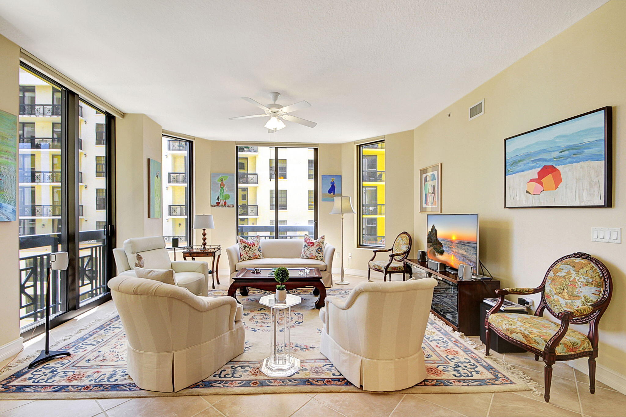 a living room with couches painting on the wall and a floor to ceiling window