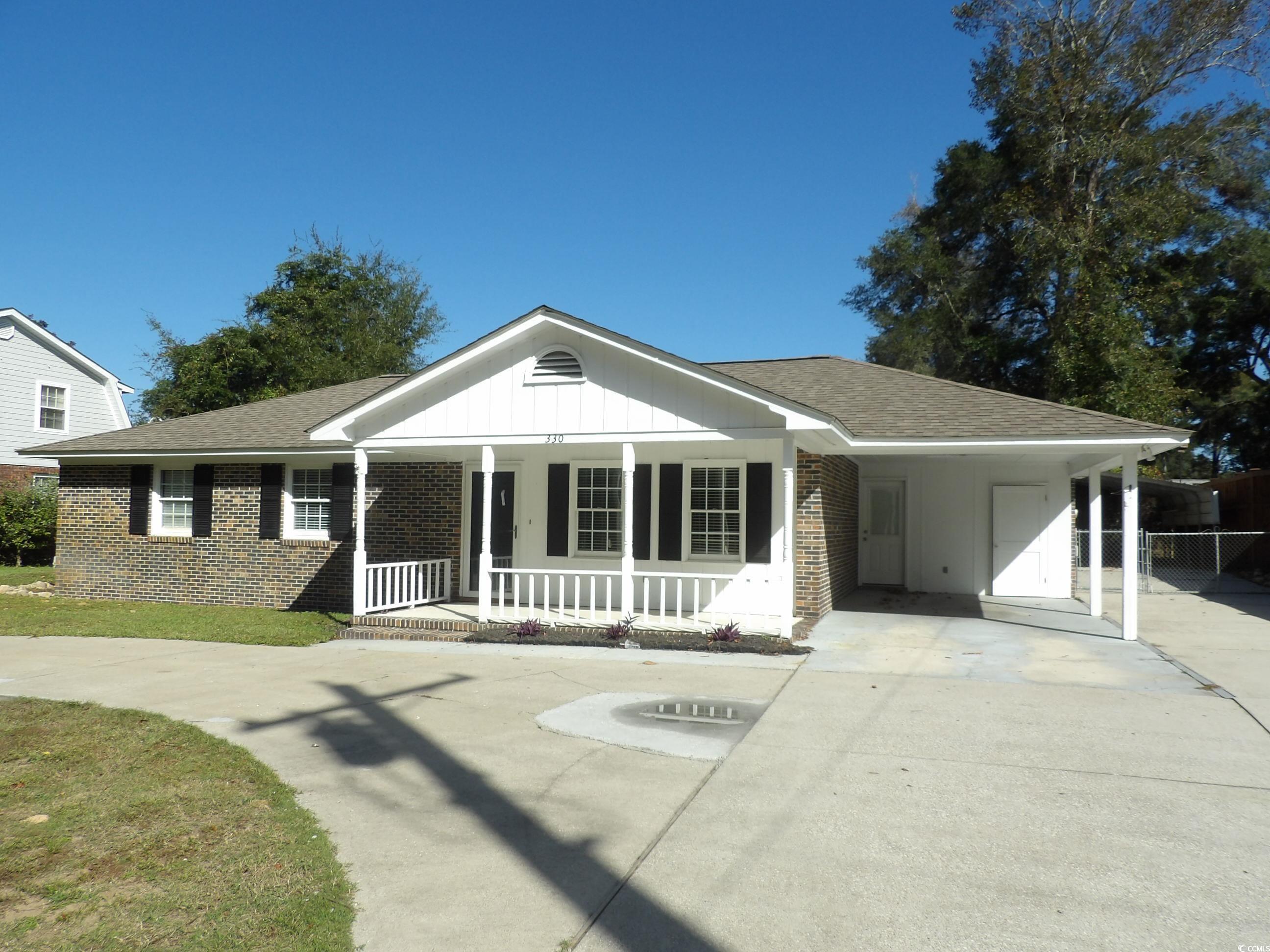 View of front of house with covered porch and a ca