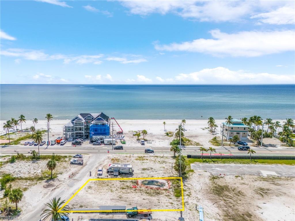 Birds eye view of property with a water view and a beach view