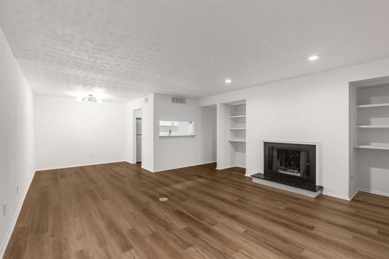 a view of empty room with wooden floor and fireplace