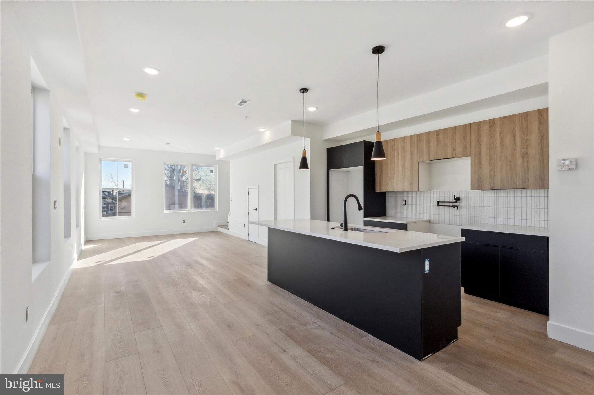 a kitchen with kitchen island granite countertop a sink cabinets and wooden floor