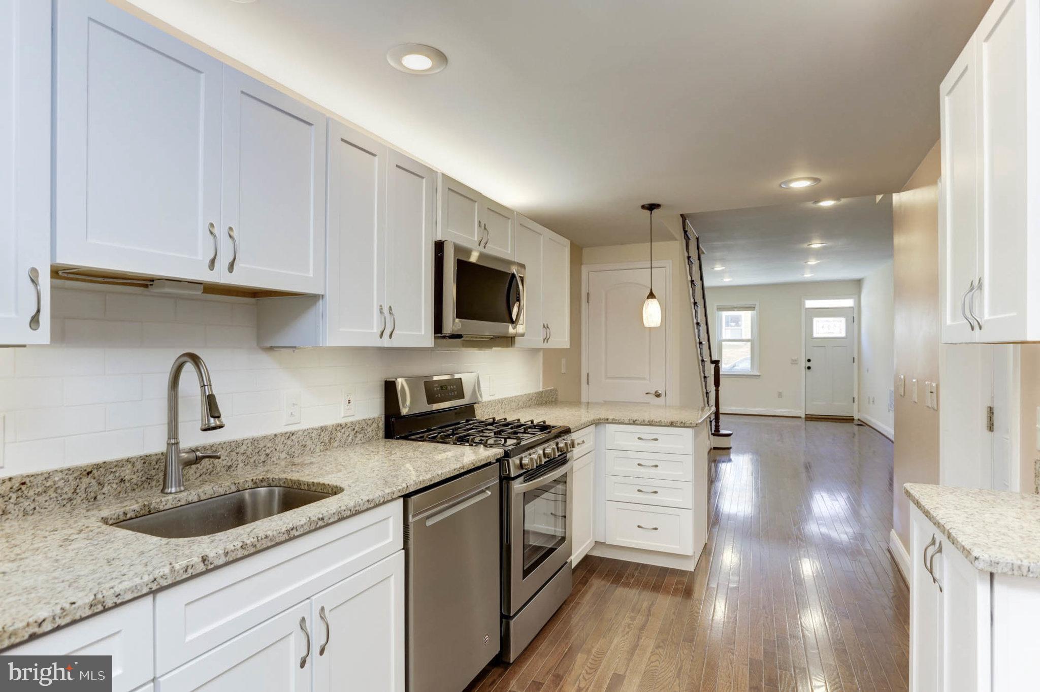 a kitchen with granite countertop a sink stainless steel appliances and white cabinets