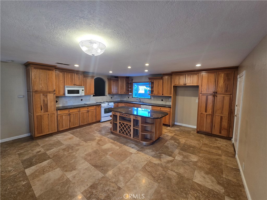 a kitchen with stainless steel appliances kitchen island granite countertop a refrigerator and a stove top oven