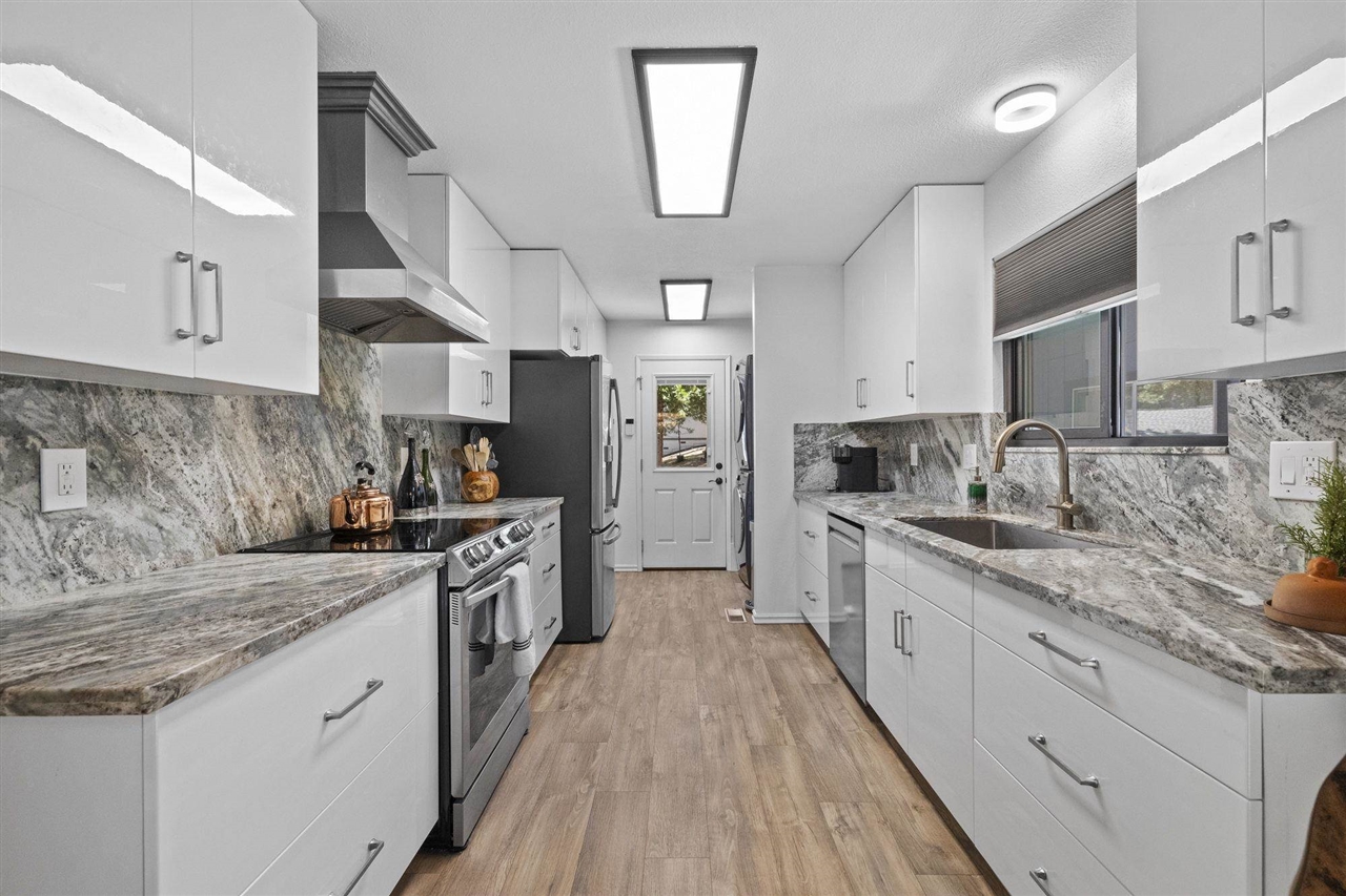 a large kitchen with stainless steel appliances granite countertop a lot of counter space and wooden floors