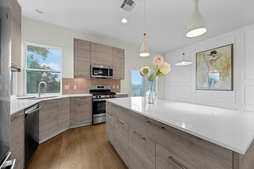 a kitchen with a sink wooden floor and stainless steel appliances