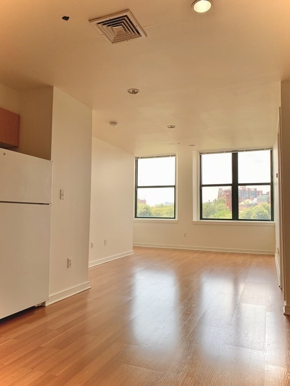 an empty room with wooden floor and windows