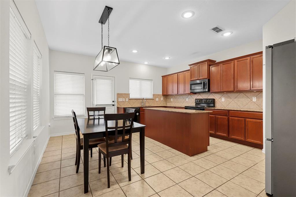 a kitchen with stainless steel appliances granite countertop a sink a stove a dining table and chairs