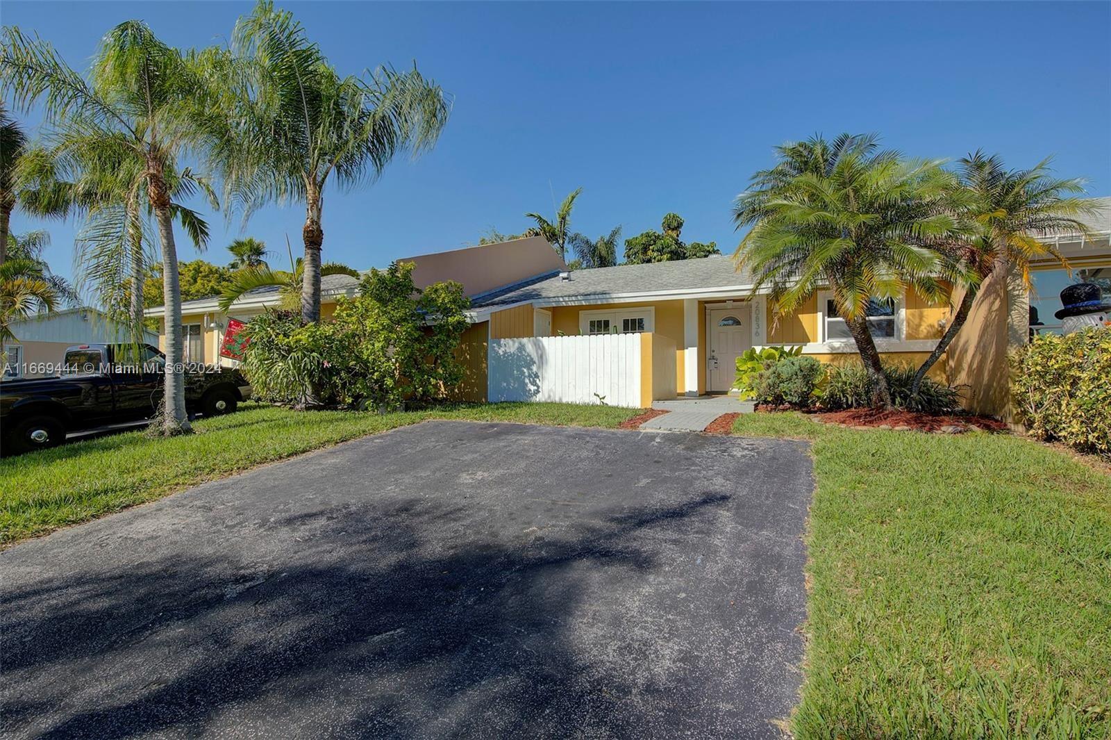 a view of a house with a yard and palm trees