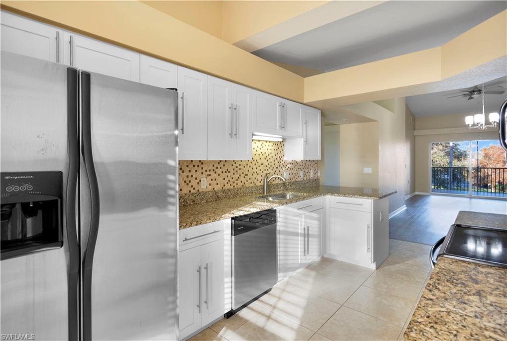 Kitchen featuring kitchen peninsula, backsplash, appliances with stainless steel finishes, white cabinetry, and sink