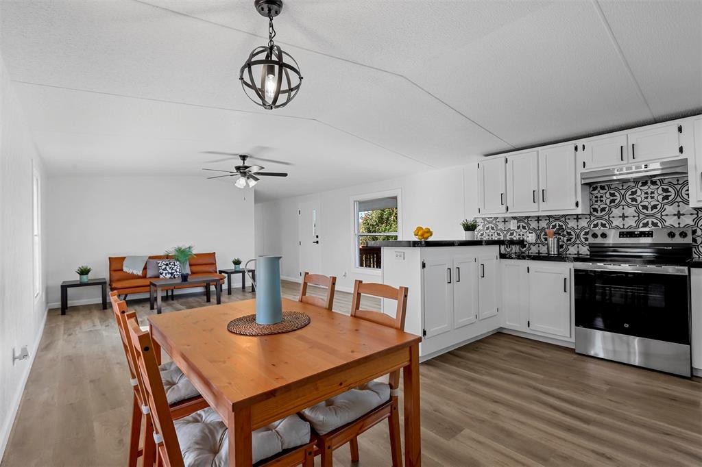 a kitchen with stainless steel appliances granite countertop a dining table chairs and white cabinets