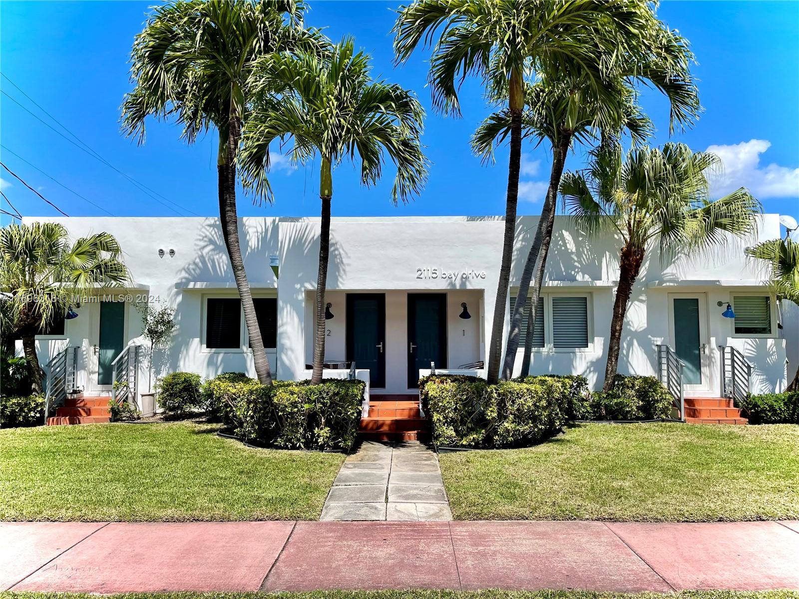 a front view of a house with a garden and palm trees