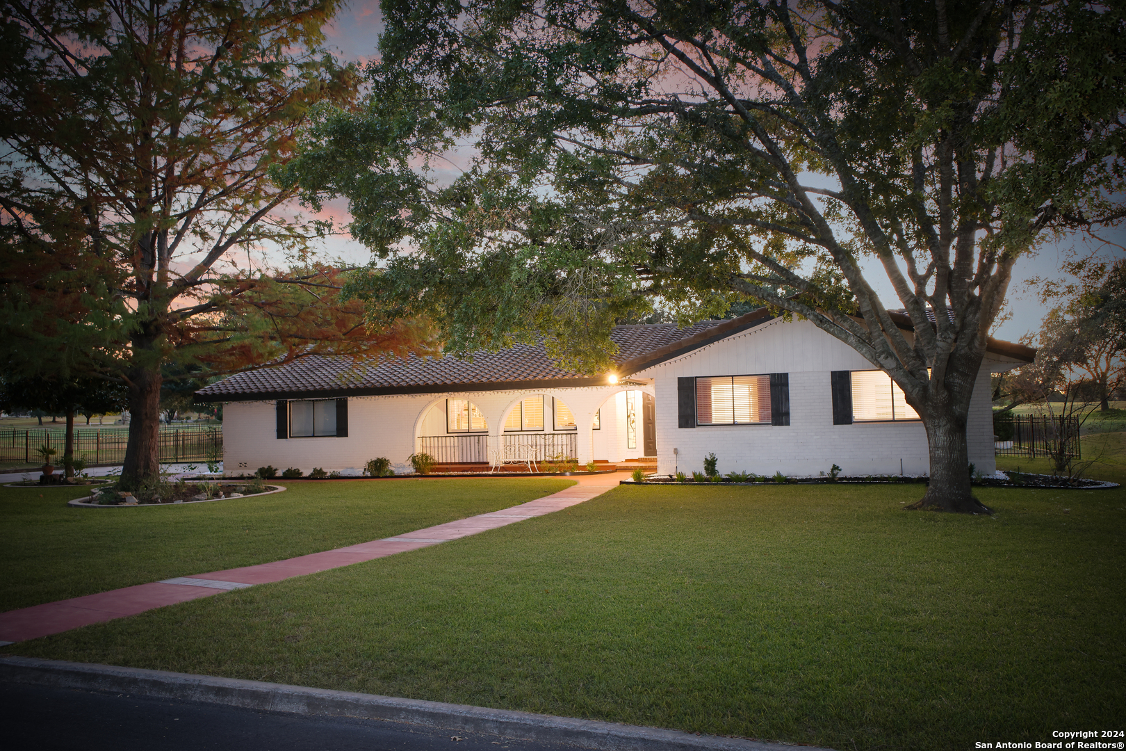 a front view of a house with a garden and trees