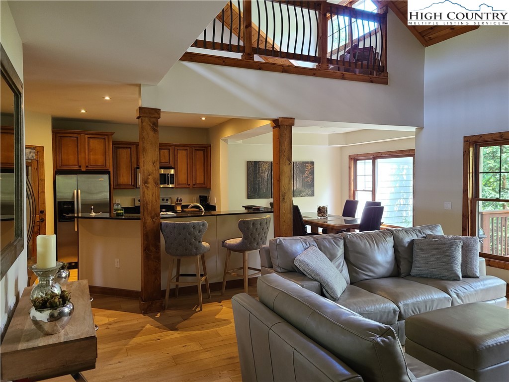 a living room with furniture a rug kitchen view and a window