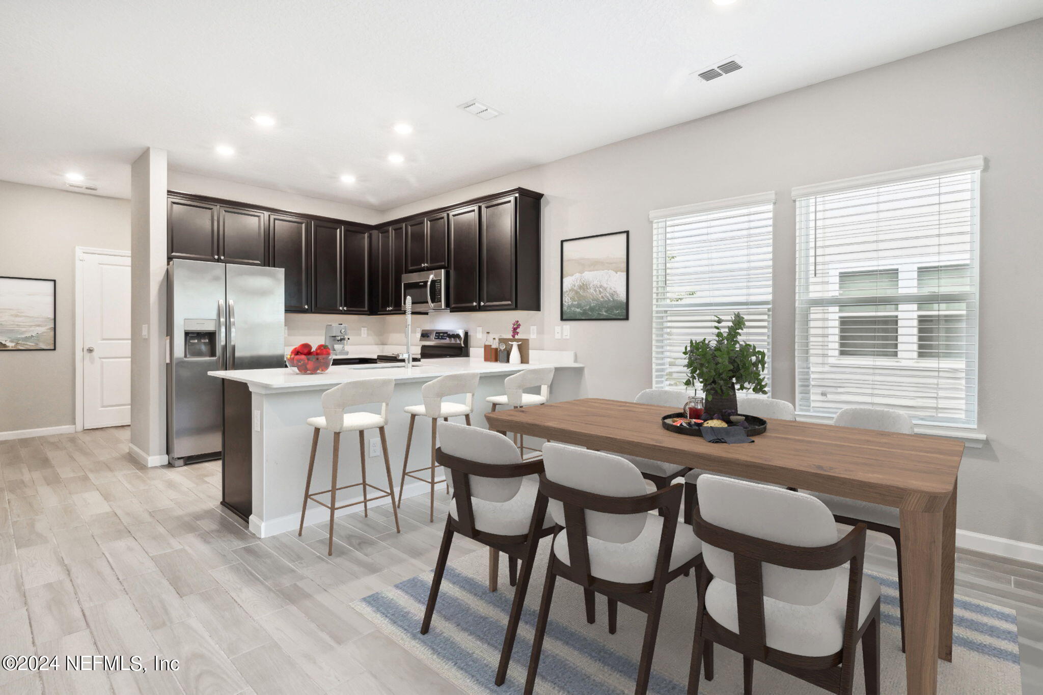 a kitchen with kitchen island granite countertop a dining table chairs and refrigerator