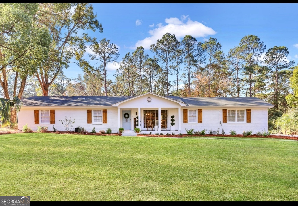 a front view of a house with a garden and trees