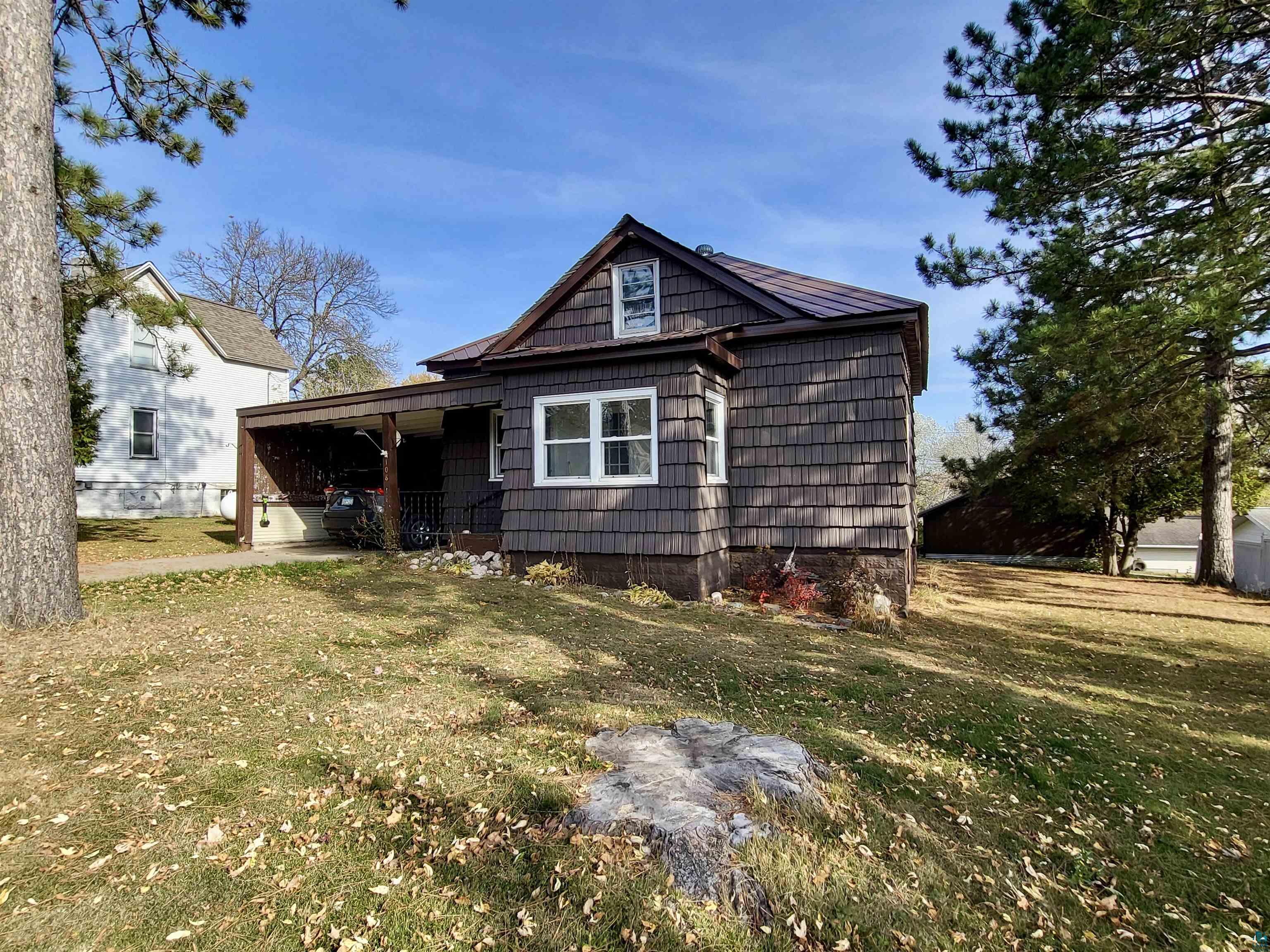 Back of house featuring a lawn and a carport