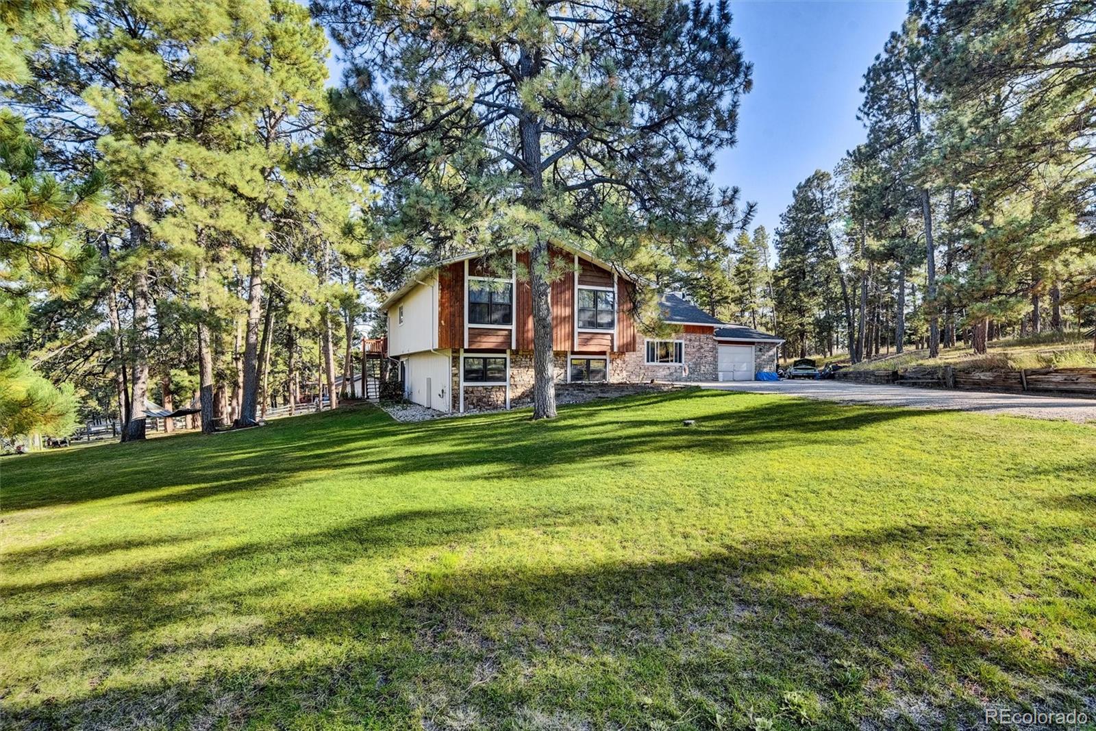 a view of a house with a big yard and large trees