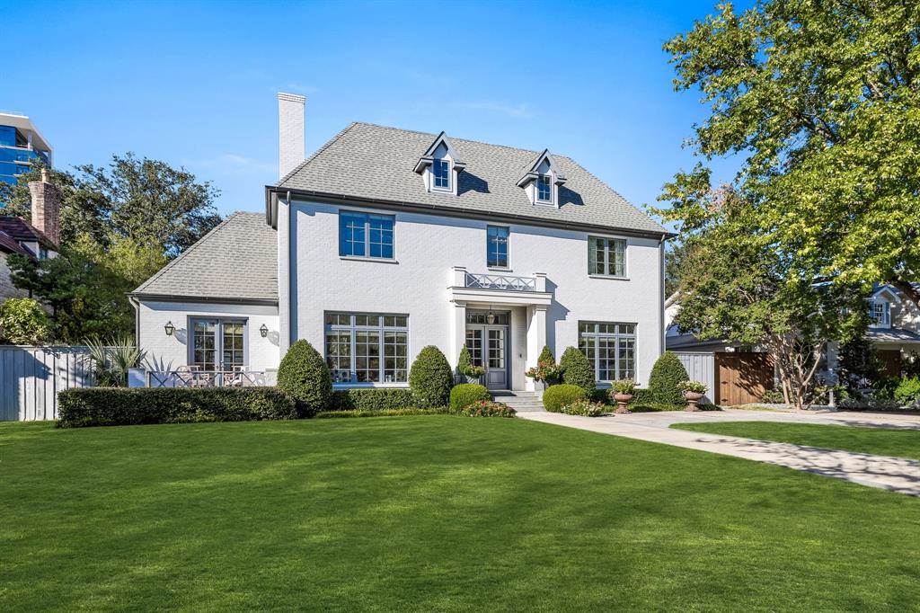 a front view of a house with a garden and trees