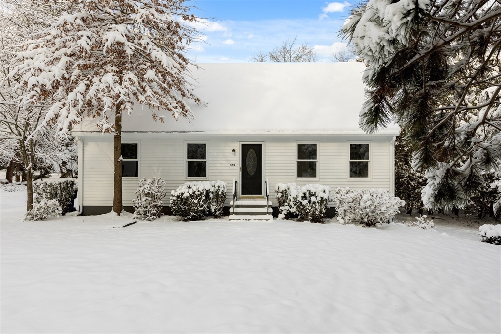 front view of house with yard and trees in the background