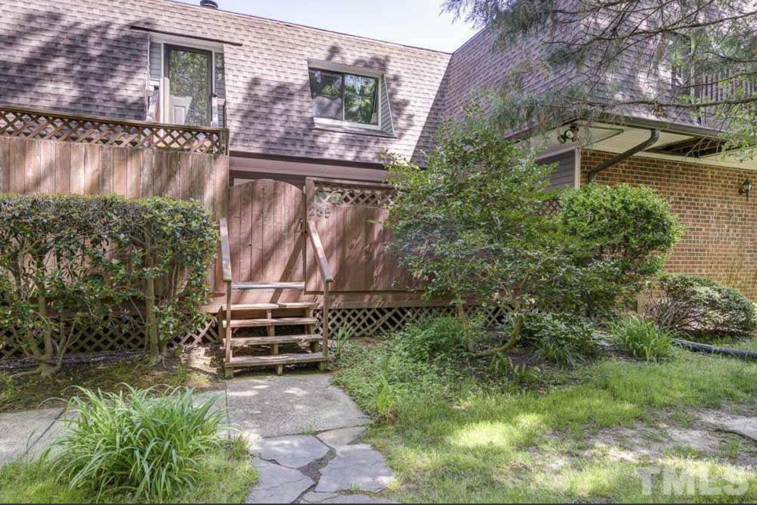 a backyard of a house with lots of green space and wooden bench