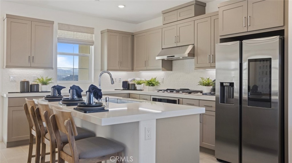 a kitchen with refrigerator a stove a sink and white cabinets