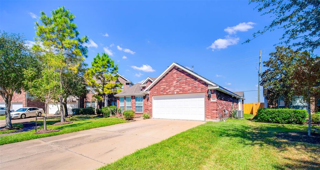 This is a single-story brick home featuring a two-car garage, well-maintained lawn, and mature trees in a suburban neighborhood.