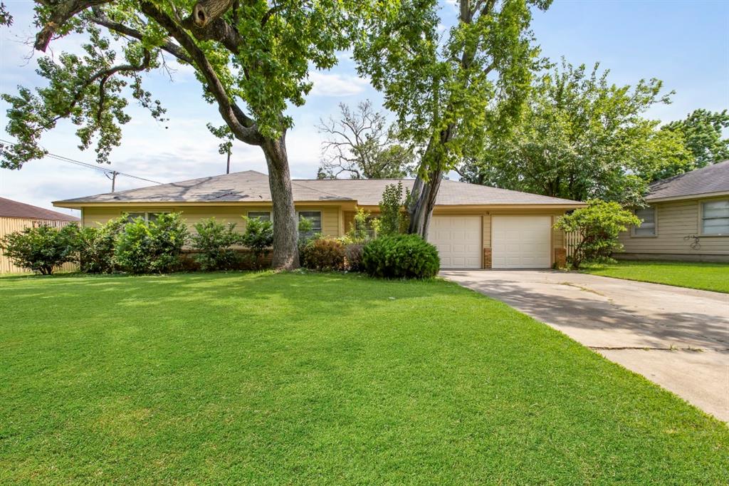 a front view of a house with a garden and tree